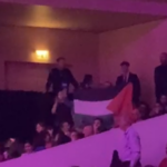 Un militant, entouré par des vigiles, déploie le drapeau palestinien.