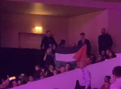 Un militant, entouré par des vigiles, déploie le drapeau palestinien.