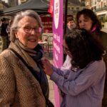 Une jeune militante de Nous Toutes accroche un badge à la veste d'une militante communiste âgée.