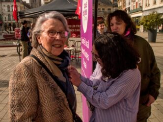 Une jeune militante de Nous Toutes accroche un badge à la veste d'une militante communiste âgée.