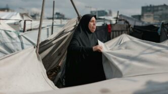 Une femme du Moyen-Orient entretient des tentes dans un camp de Gaza, symbolisant la résilience au milieu du conflit.